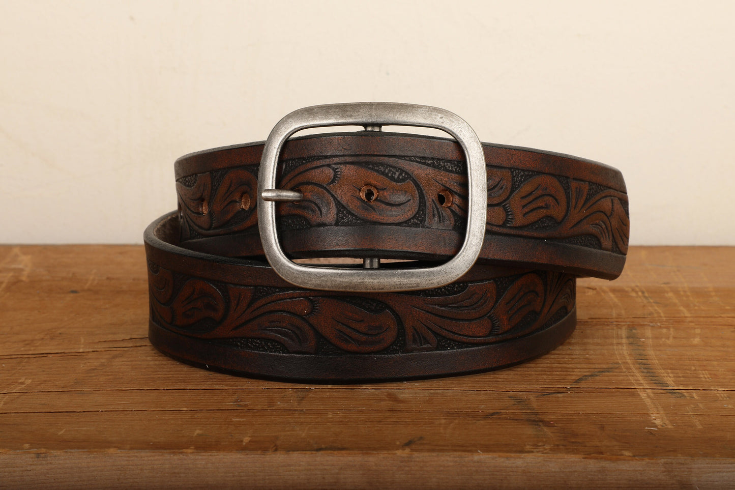 a brown belt with a metal buckle on a wooden table