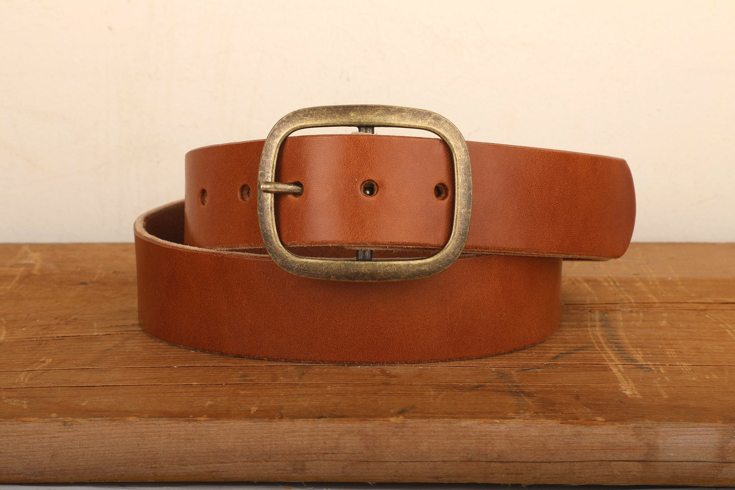 a leather belt with a metal buckle on a wooden surface