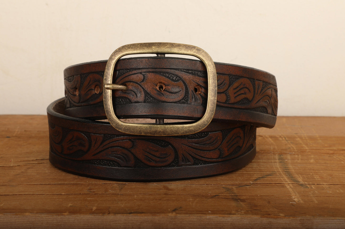 a leather belt with a metal buckle on a wooden surface