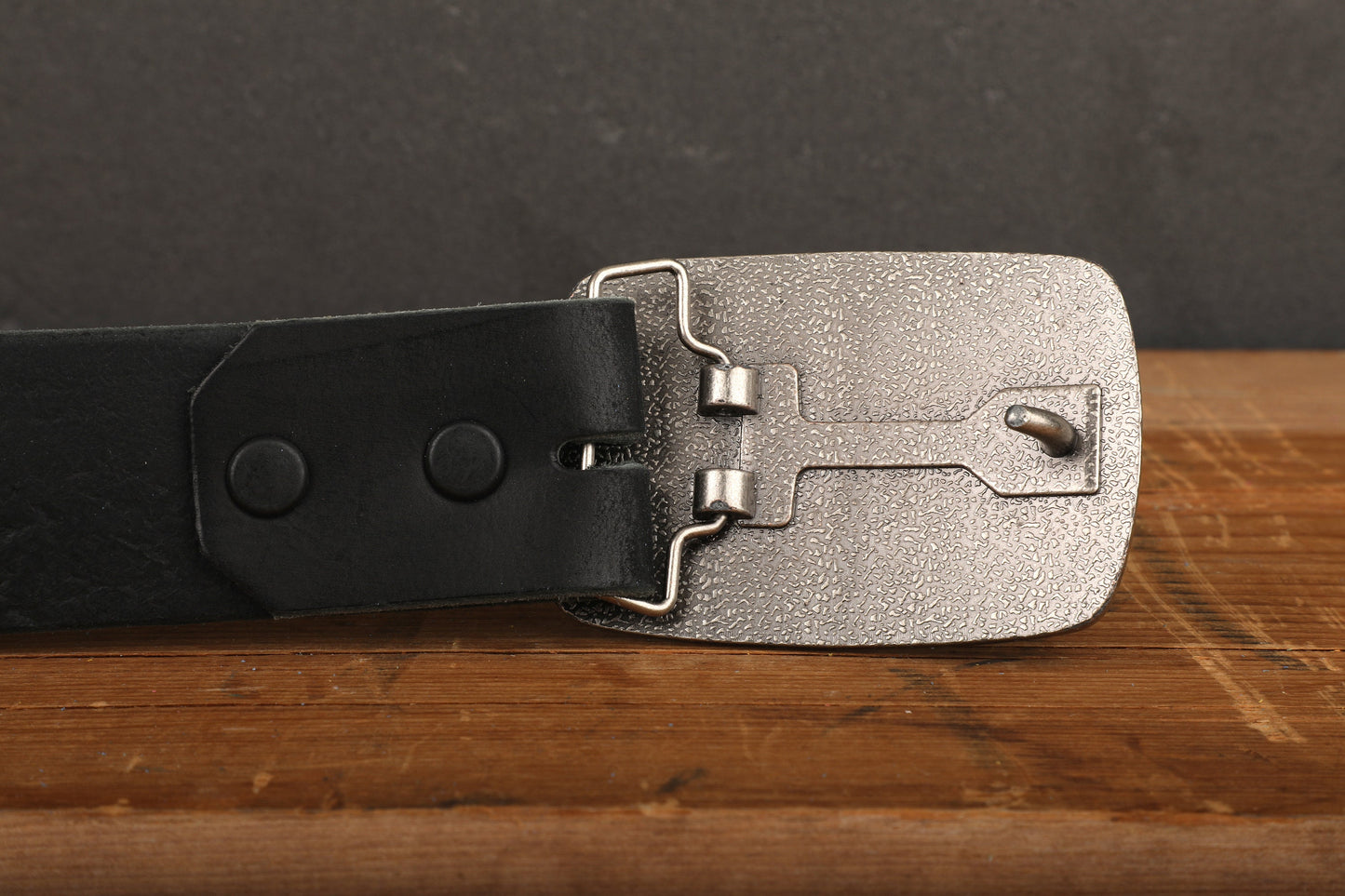 a black belt with a silver buckle on a wooden table