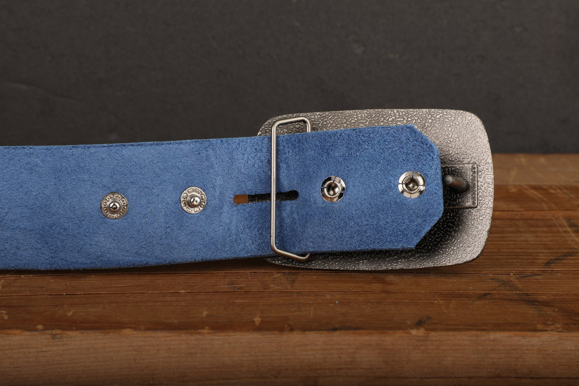 a blue belt with silver buckles on a wooden table