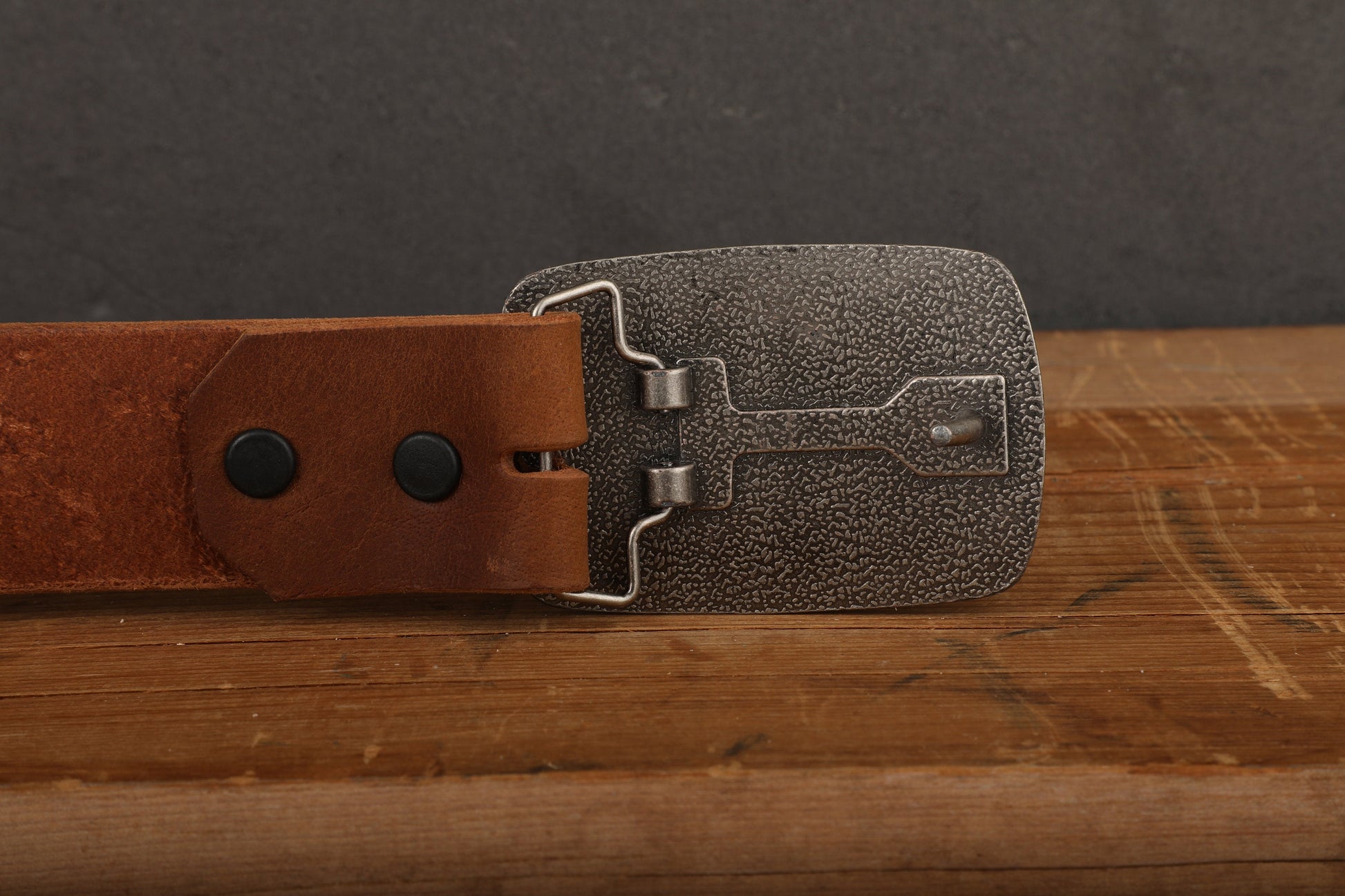 a leather belt with a metal buckle on a wooden surface